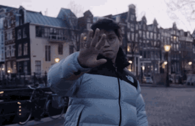 a man wearing a north face jacket is making a stop gesture