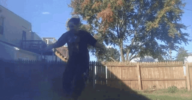 a person is standing in front of a wooden fence with trees in the background