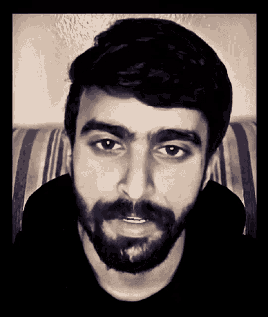 a man with a beard looks at the camera