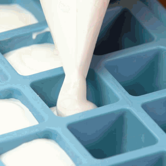 a blue ice cube tray with a white liquid poured into it