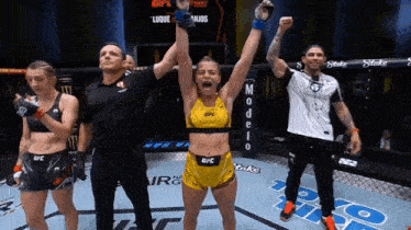 a woman in a yellow ufc outfit is holding her arms up in the air