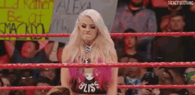 a woman is standing in a wrestling ring with a sign that says `` be of mackdown '' behind her .