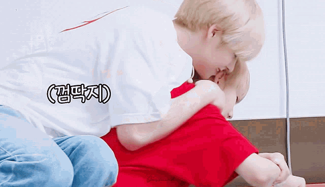 a man in a white shirt is hugging another man in a red shirt with asian writing on it