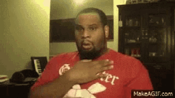 a man with a beard is wearing a red shirt and holding his chest .