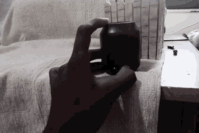a person is holding a black object in their hand and it looks like a cup