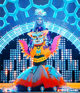 a woman in a colorful costume stands on a stage