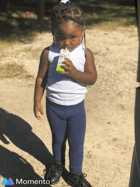 a little girl drinking from a carton that says momento