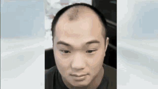 a close up of a man 's face with a shaved head .