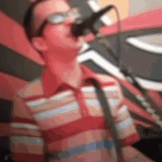 a man singing into a microphone with glasses on