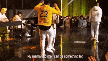 a man wearing a yellow jersey with the number 23 on it is dancing on a stage