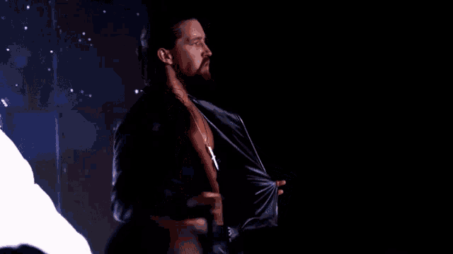 a man with long hair and a beard is taking off his shirt