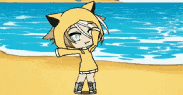 a girl wearing a yellow cat hoodie stands on a beach