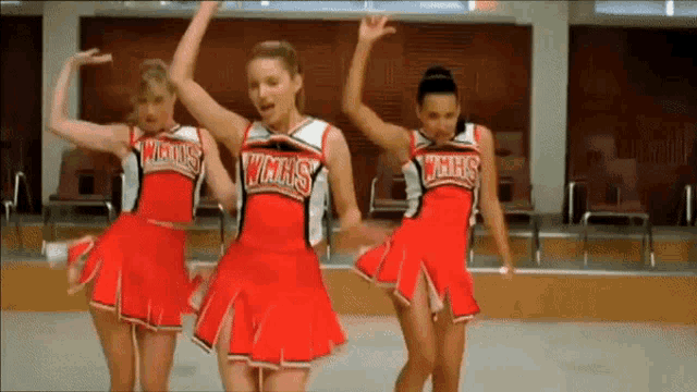 three cheerleaders from wmhs are dancing together in a gym