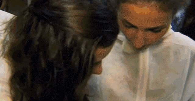 two women are kissing each other on the cheek while wearing white shirts .