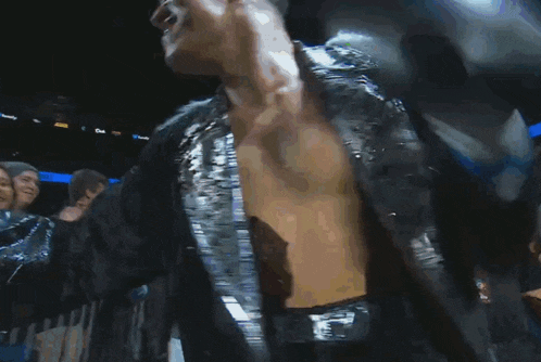 a man without a shirt is standing in front of a crowd and smiling