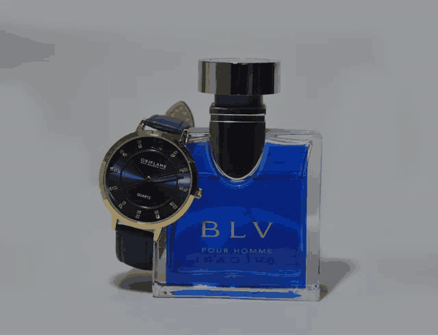 a watch sits next to a bottle of blv cologne
