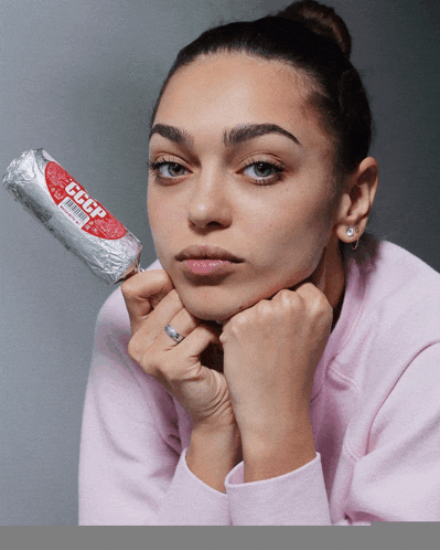 a woman in a pink sweatshirt is holding a roll of cccp sausage