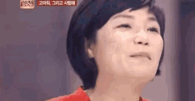a close up of a woman 's face with a red shirt on making a funny face .