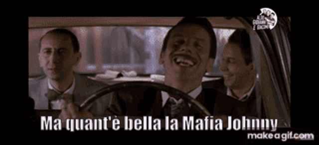 a man in a suit is laughing while driving a car .