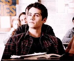 a man in a plaid shirt sits at a desk in front of a sign that says jes
