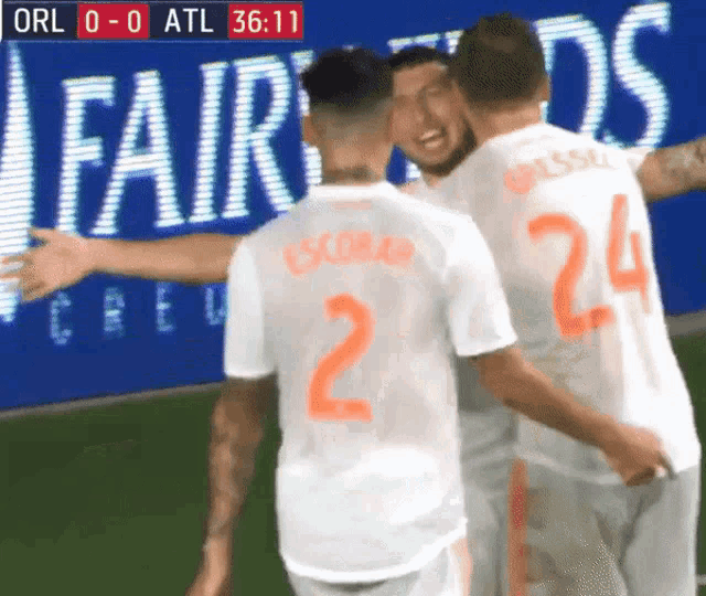 a group of soccer players are hugging each other in front of an ad for fairwinds