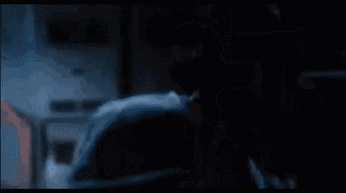 a man in a blue shirt is standing in a dark room in a movie .