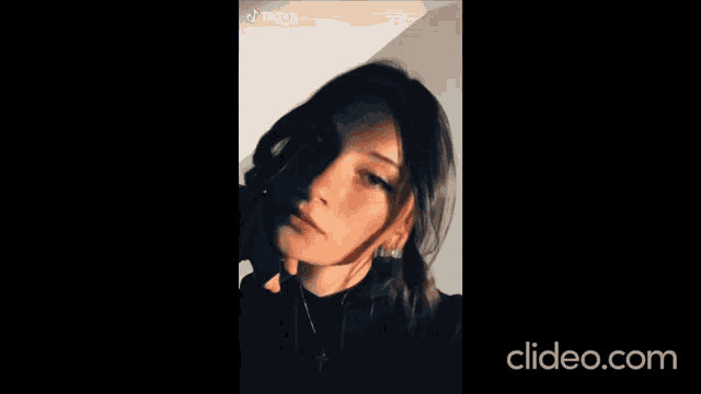a close up of a woman 's face with a black background and a tiktok logo .