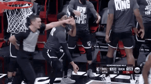 a group of men are standing around a basketball hoop wearing shirts that say king .