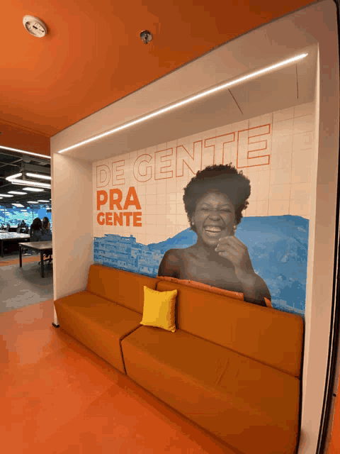 a couch with a yellow pillow sits in front of a wall that says de gente pra gente