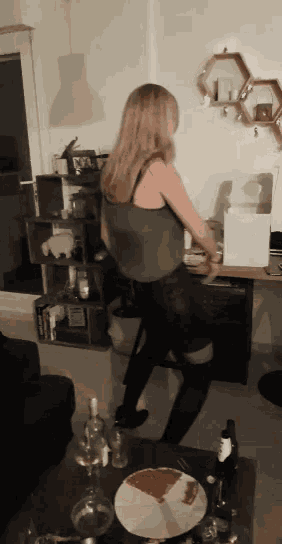 a woman is dancing in a living room with a slice of pizza on the table