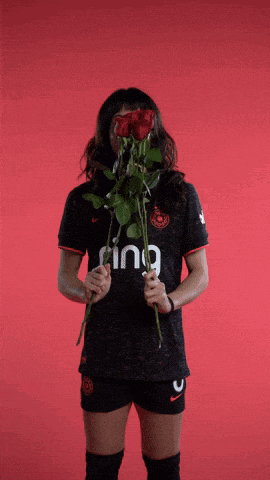 a woman in a black shirt with the word inc on it holds roses