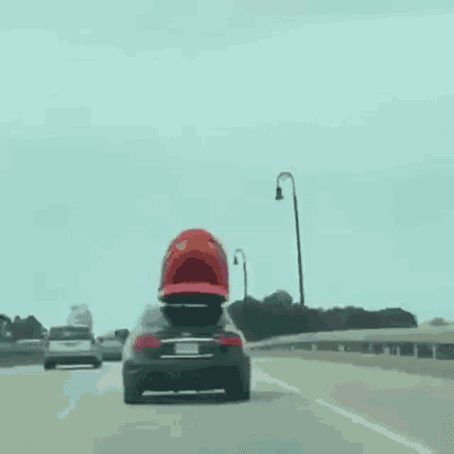 a car is driving down a highway with a kayak on the back of it .