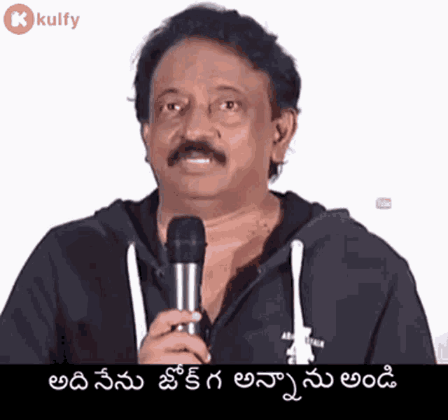 a man with a mustache is holding a microphone and speaking into it in a foreign language .