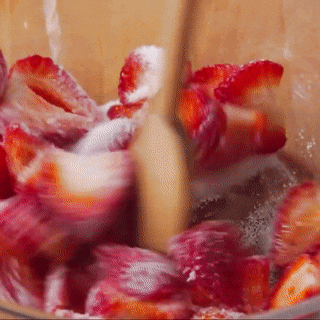 strawberries are being stirred with a wooden spoon