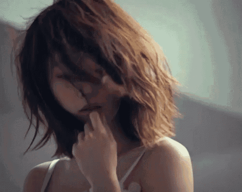 a woman with short hair is covering her face with her hand .