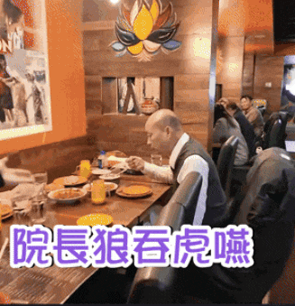 a man sits at a table in a restaurant with chinese characters on the bottom