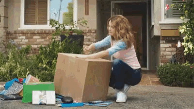 a woman squatting down with a cardboard box in front of her