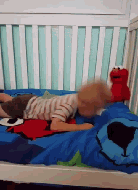a child is laying in a crib with sesame street elmo