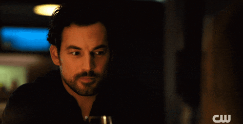 a man in a dark room with a cw logo on the bottom right