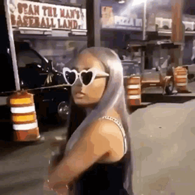 a woman wearing heart shaped sunglasses is standing on the side of the road .