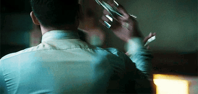 a man in a white shirt is holding a glass and smoking a cigarette