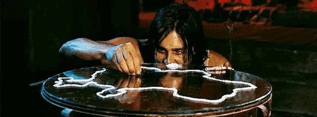 a man is sitting at a table with a map drawn on it and sniffing cocaine .