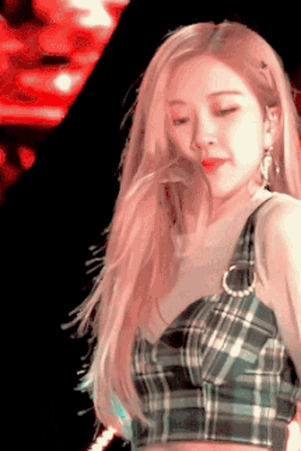 a woman wearing a plaid top and earrings looks down