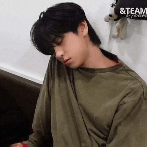 a young man is sleeping in front of a stuffed animal with the word team on it