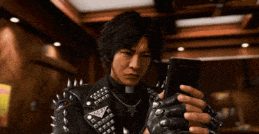 a man in a leather jacket with spikes is holding a phone