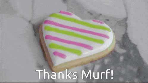 a person holding a heart shaped cookie that says thanks murf on the bottom