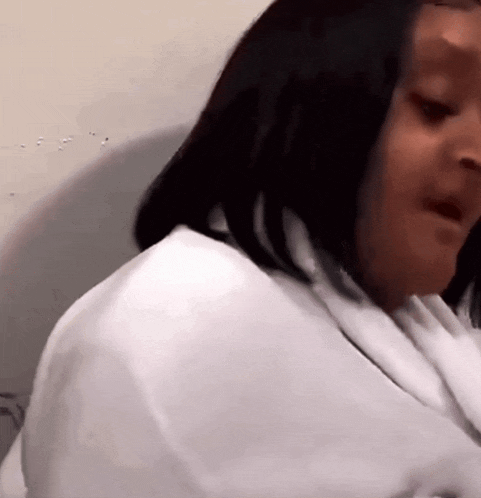 a woman in a white shirt is sitting on a toilet .
