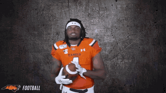 a football player holds a ball in his hands with the word football behind him