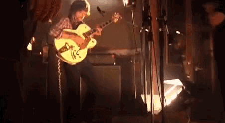 a man is playing a guitar on stage in front of a microphone .