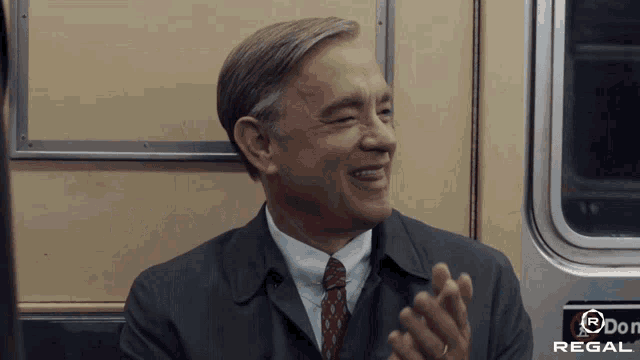 a man in a suit and tie is applauding on a regal train